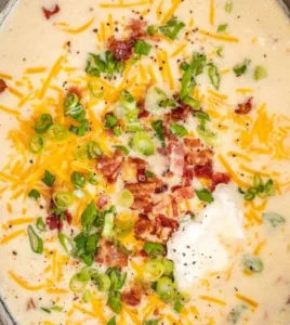 Bowl of creamy Crockpot potato soup garnished with herbs and served with bread